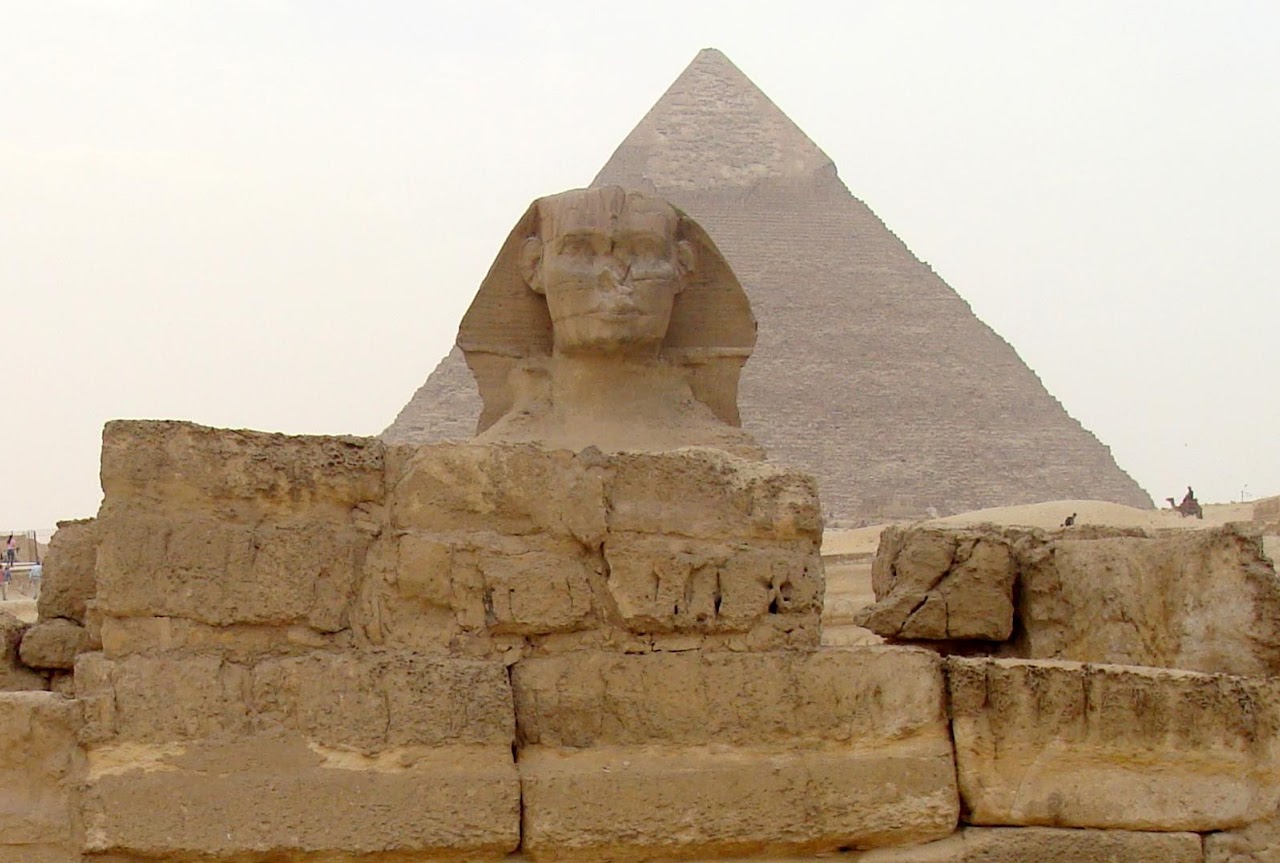 A view west from within the Sphinx Temple showing the limestone blocks of the temple wall with the Great Sphinx and Pyramid of Khafre behind.